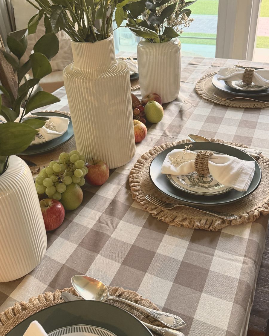 A table laid with a taupe gingham cloth, white roses and woven placemats