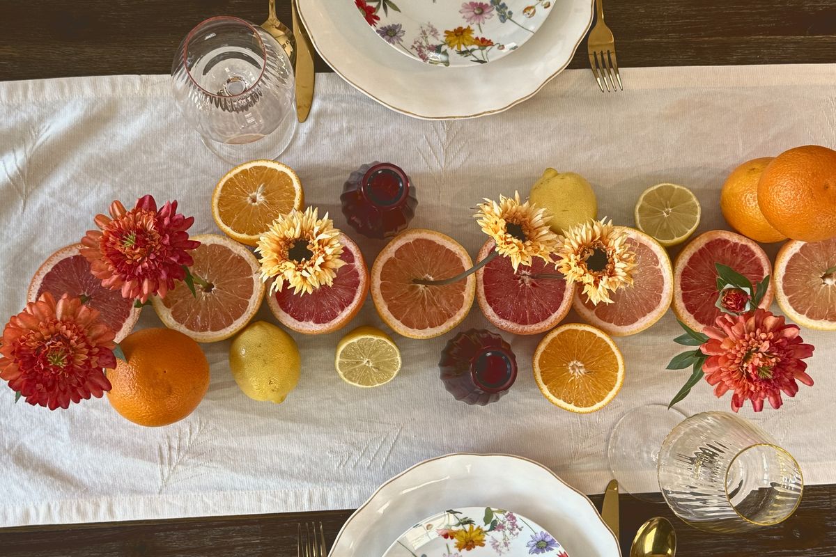 Grapefruit, oranges, lemons and dahlias laid along a white linen runner